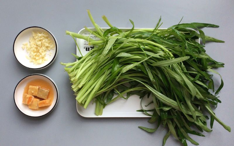 Ingredients for stir-fried water spinach with garlic include fresh green water spinach, garlic, cooking oil, and basic seasonings.