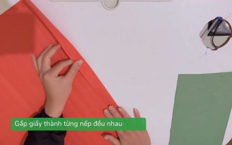 Người dùng gấp từng nếp giấy đều nhau chuẩn bị làm quạt giấy.