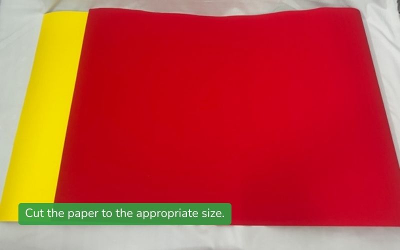 A rectangular sheet of colored paper, pre-cut in preparation for folding a decorative paper fan for Tet