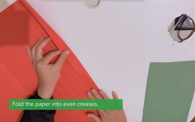 The user folds each crease of paper evenly in preparation for making a paper fan