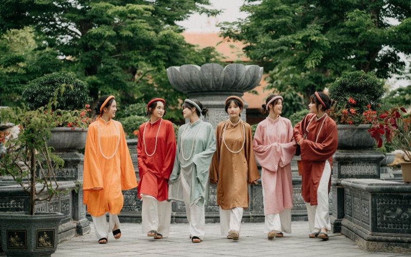 Posing for photos wearing a traditional Vietnamese dress (áo dài) for Tet at the museum, with its ancient architectural setting, in a gentle and elegant pose.