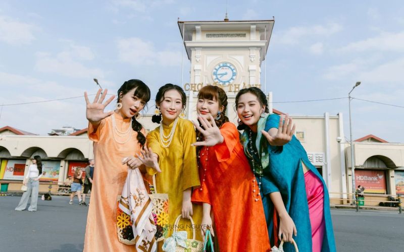 A group of friends pose for photos wearing traditional Vietnamese ao dai in various distinct colors for Tet (Lunar New Year).