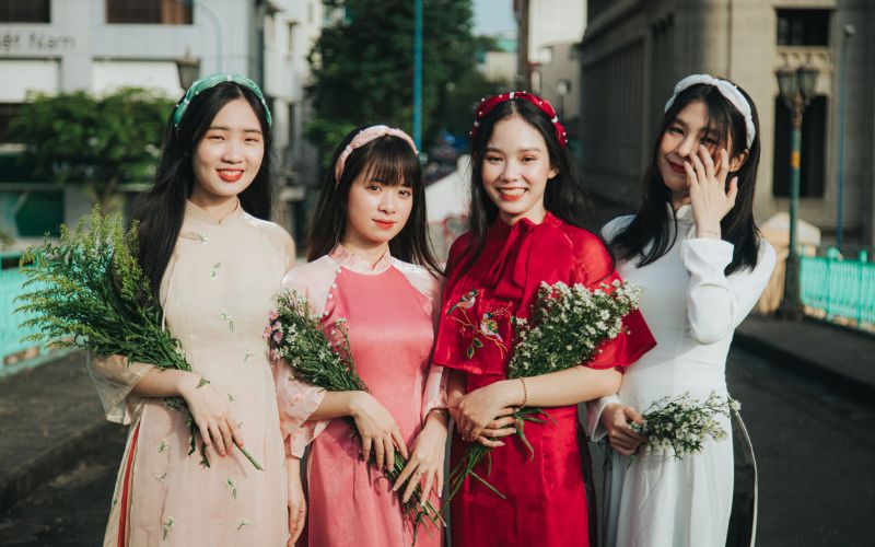 Taking photos in traditional Vietnamese ao dai for Tet (Lunar New Year) with floral and fan accessories, creating a striking focal point.